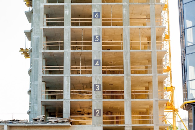 Edifício moderno em detalhes de construção, moldura de concreto, aberturas de janelas e andaimes.