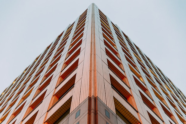 Edifício moderno, filmado a partir de baixo com céu claro no fundo à noite