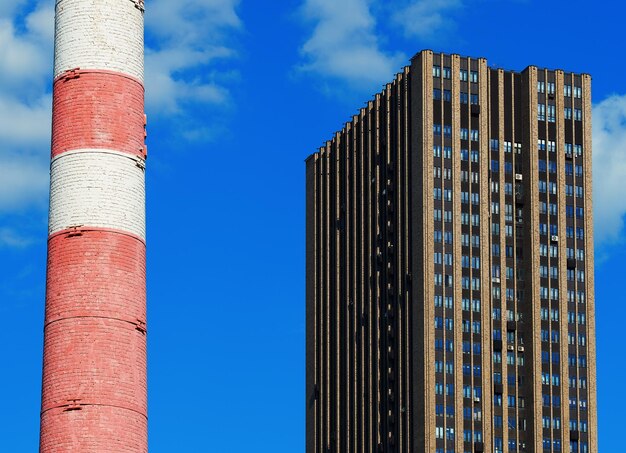 Foto edificio moderno de gran altura cerca de la vieja chimenea de la fábrica roja y blanca