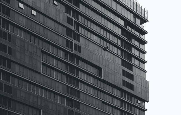 Edificio de oficinas de varios pisos con ventana de cristal de limpieza trabajador