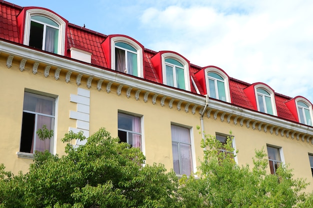 Edifício ornamentado com janelas abertas atrás de folhagem verde para o conceito de ficar em casa