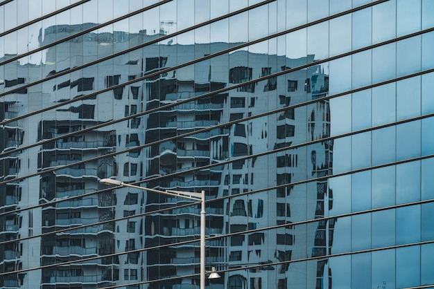 Foto edifício refletido em uma fachada de vidro