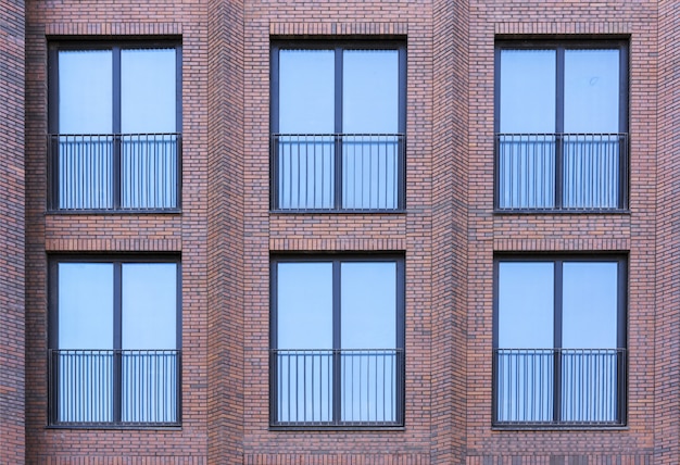 Edifício residencial em estilo loft. Grandes janelas em uma parede de tijolo vermelho.