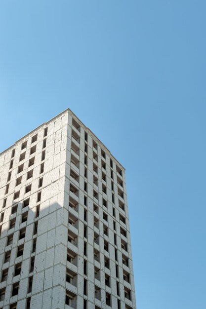 Edificio residencial de varios pisos en construcción y grúa sobre un fondo de cielo azul