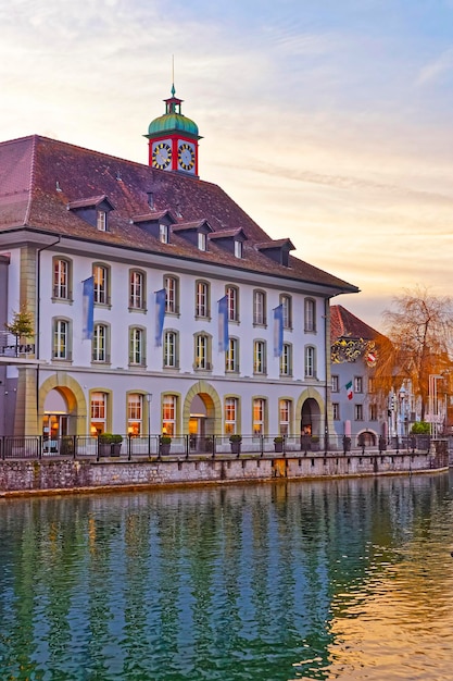 Edificio con una torre de reloj en el terraplén del casco antiguo de Thun. Thun es una ciudad en el cantón suizo de Berna, donde el río Aare fluye desde el lago Thun.