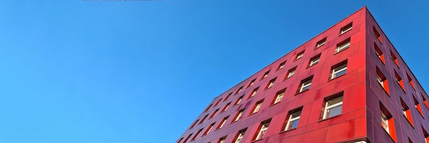 Edifício vermelho de vários andares em pé contra o fundo do céu azul