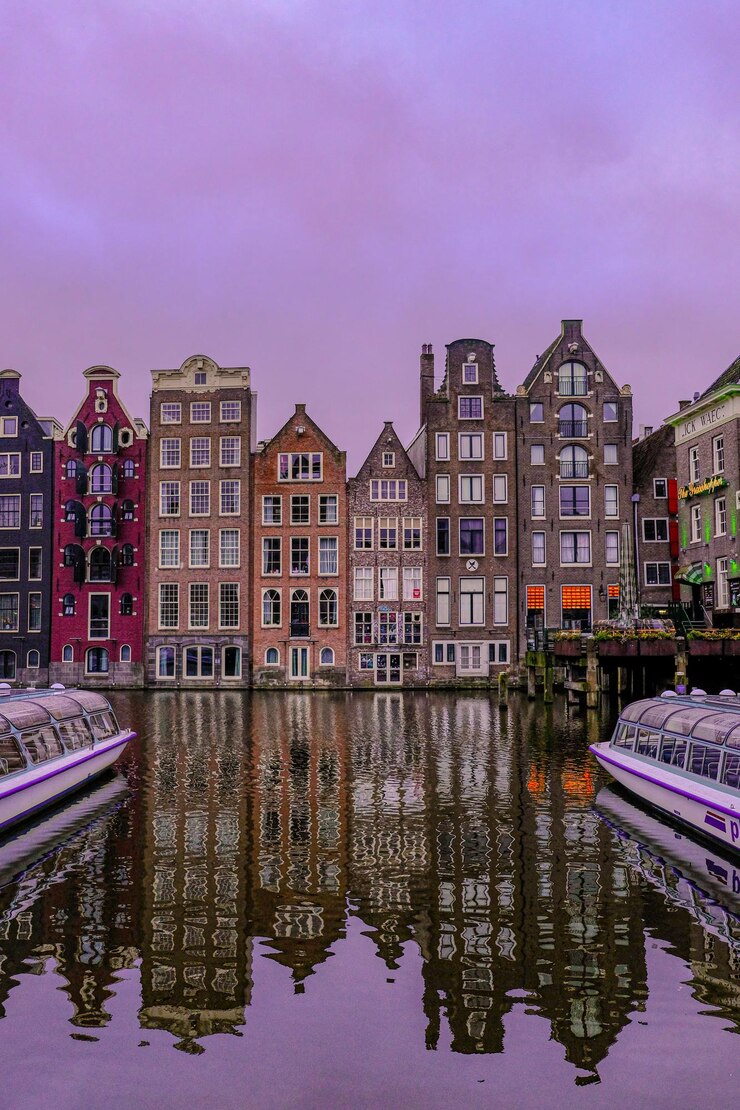 Edifícios de arquitetura iluminados em Damrak durante o nascer do sol em Amsterdã