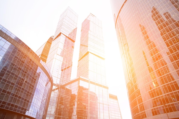 Edifícios de torre de vidro de baixo ângulo de arranha-céus no distrito comercial com escritórios financeiros no pôr do sol