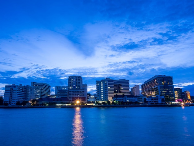 Foto edifícios do hospital siriraj ao longo do rio chao phraya em bangkok sob o céu nublado crepuscular do pôr do sol na noite tailândia