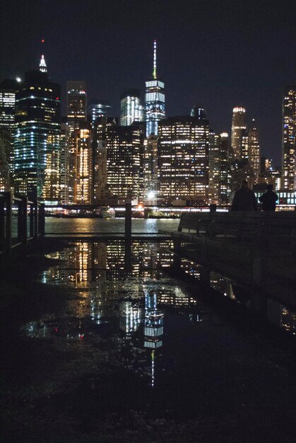 Foto edifícios iluminados ao lado do rio na cidade à noite