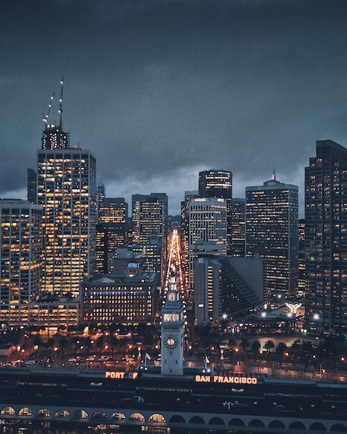 Foto edifícios iluminados contra o céu nublado ao anoitecer