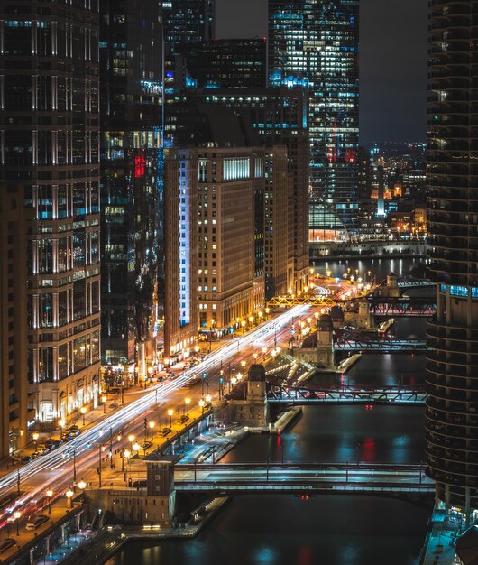 Foto edificios iluminados por puentes sobre el río en la ciudad por la noche