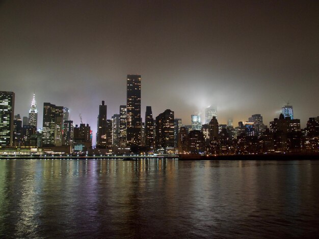 Edificios iluminados por el río contra el cielo en la ciudad por la noche