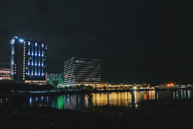 Foto edificios iluminados por el río contra el cielo por la noche