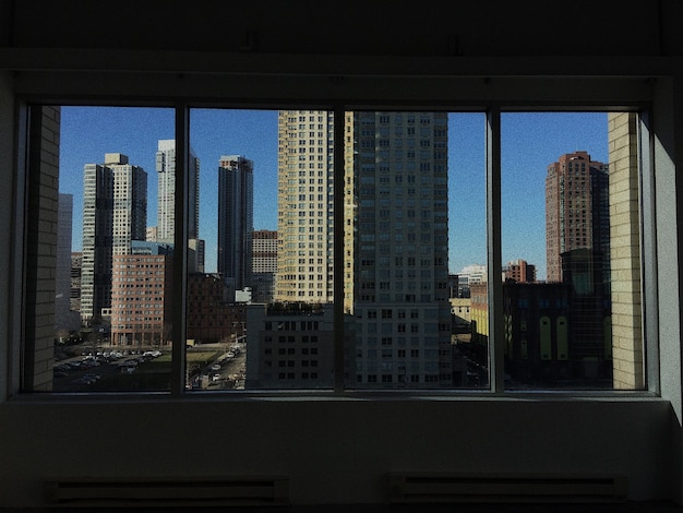 Edificios modernos contra un cielo despejado vistos a través de una ventana de vidrio