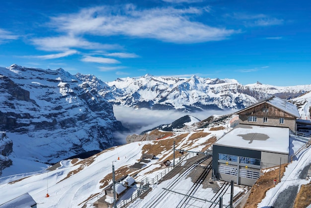 Edificios y vías férreas con majestuosas montañas nevadas