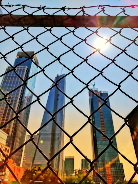 Foto edificios vistos a través de la valla de enchaines durante la puesta de sol