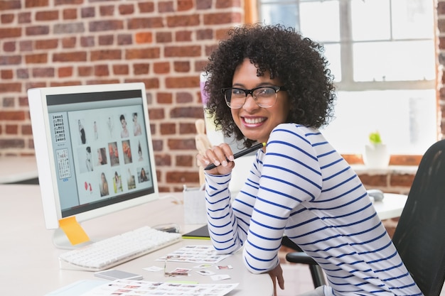 Editor de fotos femenino sonriente en el escritorio de oficina