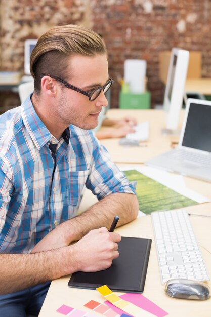 Editor de fotos masculino con digitalizador en la oficina