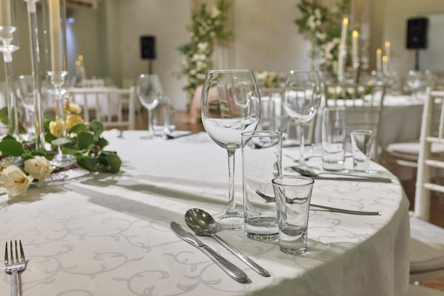 Edler Tisch mit einem Blumenstrauß Luxus-Essset mit Besteck, Serviette, Geschirr und mit einer Tischdecke bedeckt im Restaurant