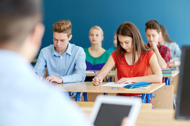 educação, aprendizagem e conceito de pessoas - grupo de alunos com livros escrevendo teste escolar