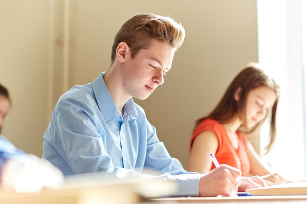 educação, aprendizagem e conceito de pessoas - grupo de alunos com livros escrevendo teste escolar