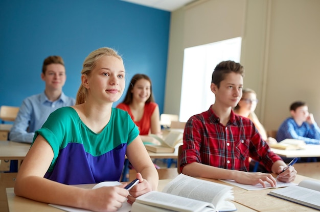 Foto educação, aprendizagem e conceito de pessoas - grupo de alunos com livros na aula escolar