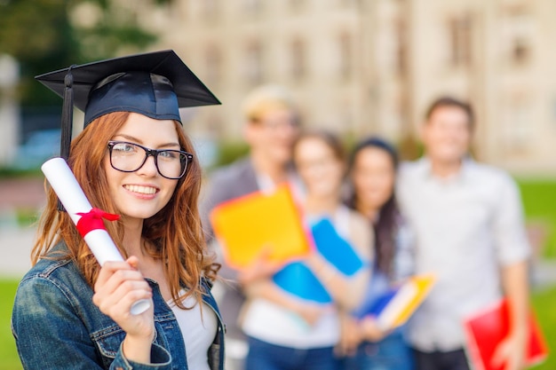 educação, campus e conceito adolescente - adolescente sorridente na tampa de canto e óculos com diploma e colegas nas costas