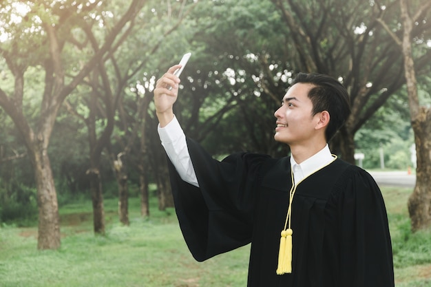 educação, conceito de graduação - homens de vestidos de bacharel feliz ao ar livre em natural