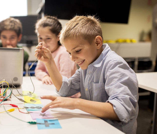 educação, crianças, tecnologia, ciência e conceito de pessoas - grupo de crianças felizes com computador portátil brincando com kit de invenção na aula de robótica