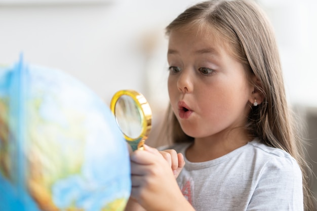 Educação e conceito de escola. menina criança apontando para o globo.