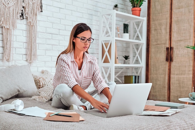 Educação e trabalho on-line à distância Empresária feliz trabalhando no escritório trabalha remotamente em casa na cama