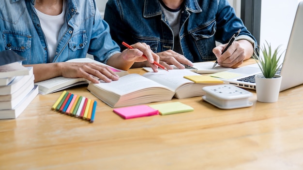 Educação, ensino, aprendizagem, tecnologia e conceito de pessoas. Dois alunos do ensino médio ou colegas de turma com ajuda amigo fazem lição de casa aprendendo em sala de aula, livros de tutor com os amigos