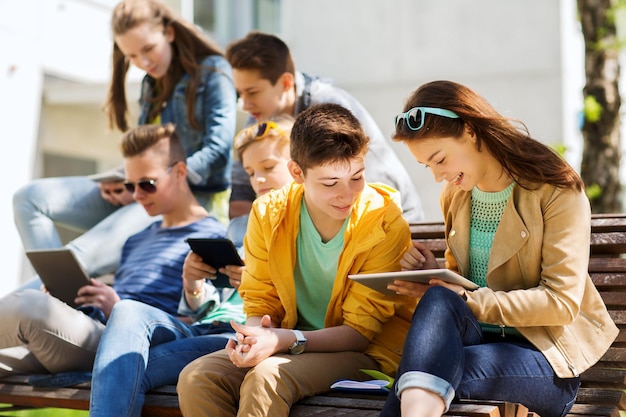 educação, ensino médio e conceito de pessoas - grupo de estudantes adolescentes felizes com computadores tablet pc no pátio do campus