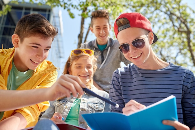 Foto educação, ensino médio e conceito de pessoas - grupo de estudantes adolescentes felizes com notebooks aprendendo no pátio do campus