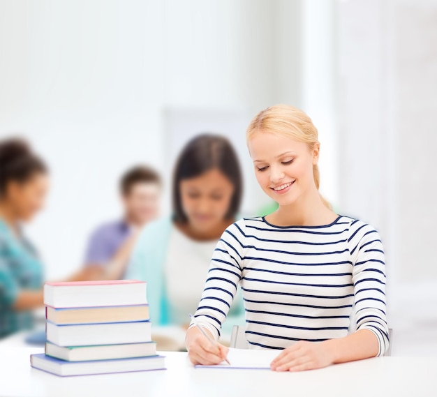 educação, escola e conceito de negócios - mulher sorridente com livros e cadernos estudando na faculdade