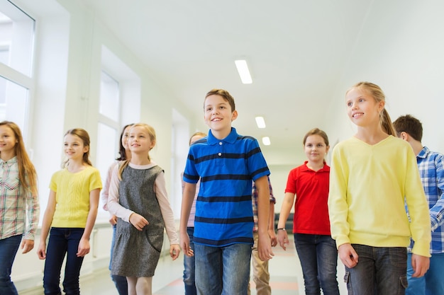 educação, escola primária, bebidas, crianças e conceito de pessoas - grupo de crianças de escola sorridentes andando no corredor