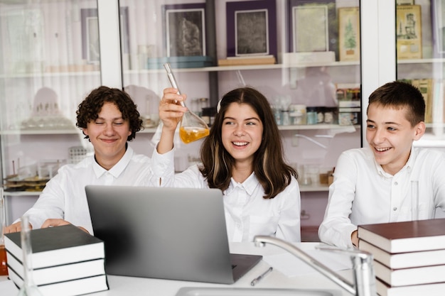 Educação escolar Colegas alegres na aula de química seguram frascos com líquido para experimentos Amigos felizes estudam juntos na aula no laboratório