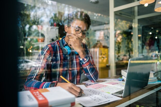 Educação escolar. Estudante sério e atencioso fazendo anotações enquanto se concentra em sua tarefa