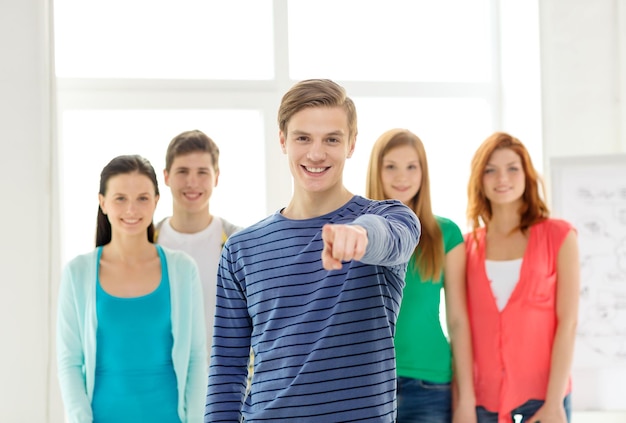 Educação, gesto e conceito de escola - grupo de estudantes sorridentes com adolescente na frente apontando para você