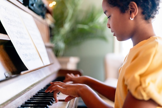 Educação musical. garota negra feliz tocando piano em casa