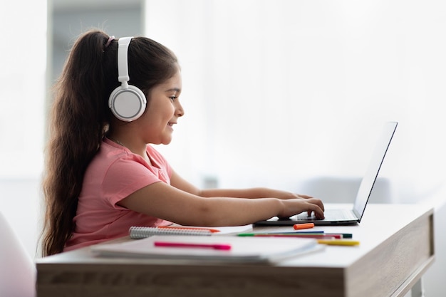 Educação on-line menina do Oriente Médio em fones de ouvido usando laptop em casa