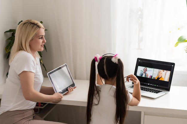 Educação online de crianças. Mãe e filha de pré-escola assistindo a uma aula de vídeo em casa.