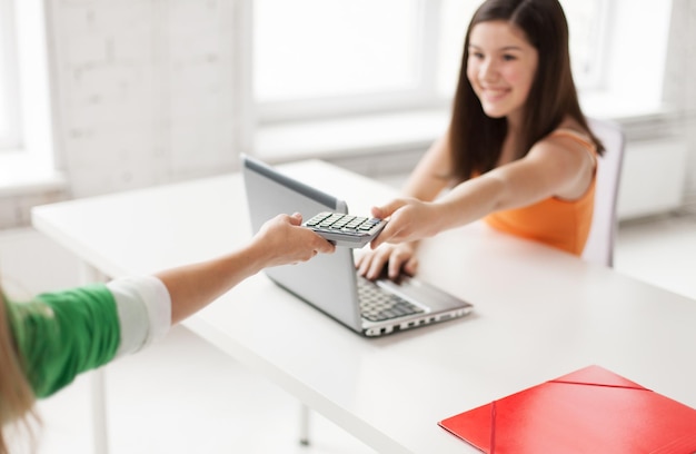 Foto educação, pessoas, amizade, tecnologia e conceito de ensino médio - close-up de estudantes do sexo feminino com calculadora de compartilhamento de laptop na escola