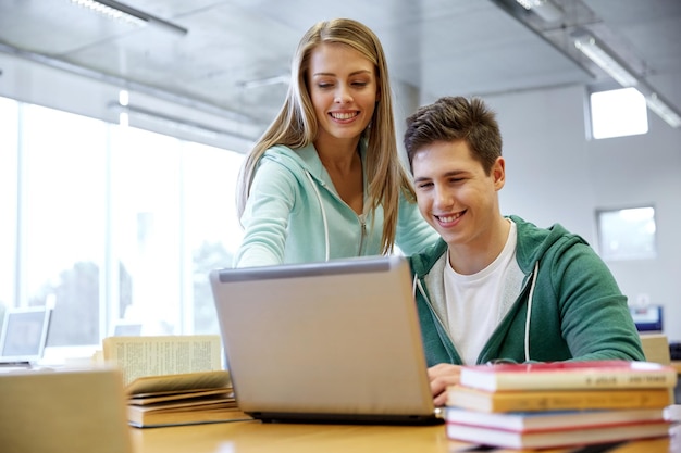 educação, pessoas, tecnologia e conceito de aprendizagem - estudantes felizes do ensino médio com computador portátil em sala de aula ou biblioteca