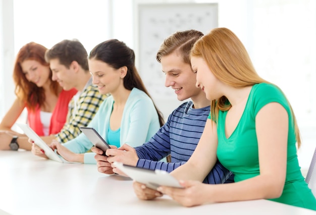 educação, tecnologia e conceito de internet - alunos sorridentes com computadores tablet pc na escola