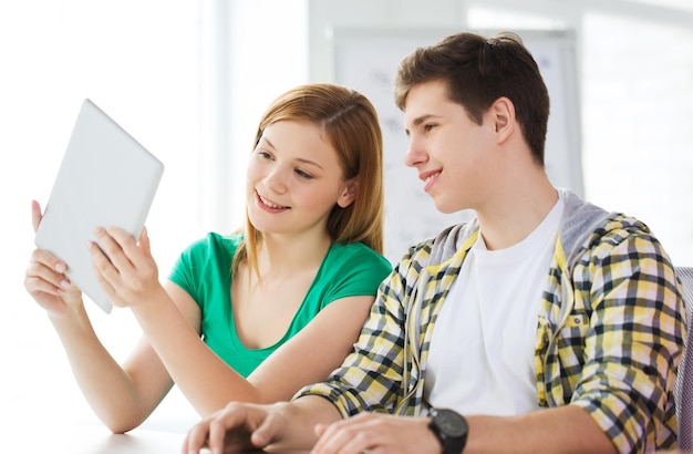 Educação, tecnologia e conceito de internet - alunos sorridentes com computadores tablet pc na escola