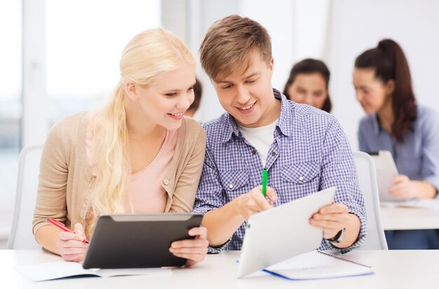 Educação, tecnologia e conceito de internet - dois alunos sorridentes com tablet pc e notebooks na escola