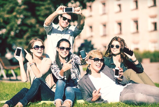 educação, tecnologia, internet, férias de verão, redes sociais e conceito de adolescente - grupo de adolescentes com smartphones