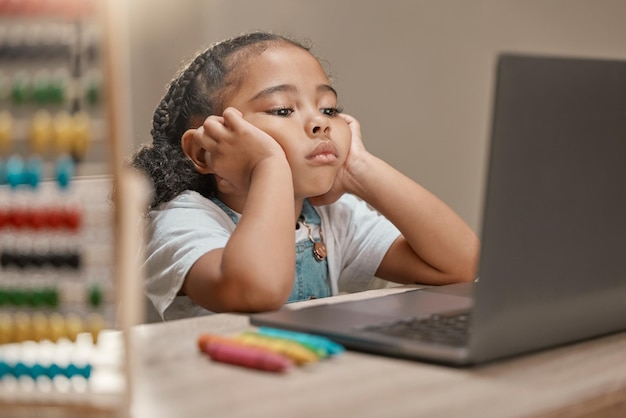 Foto educação triste e criança com laptop para estudar online e ouvir uma aula de videochamada em casa tdah cansado e garota entediada com um computador para problemas de aprendizado e aprendizado eletrônico